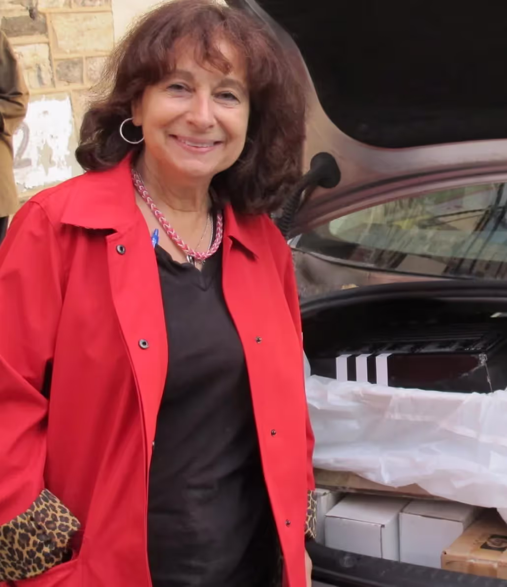 A woman in a red jacket standing next to a car